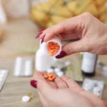 Close-up of a person pouring small round orange pills out of a bottle into their hand